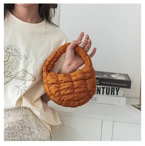 Vista dettagliata di una mini borsa a mano trapuntata arancione tenuta da una modella.