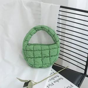 Mini bolso de mano acolchado verde con diseño de nube en una silla minimalista