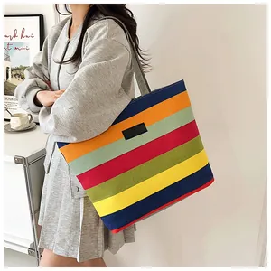 Close-up detail of a large colorful striped canvas tote bag with black logo patch