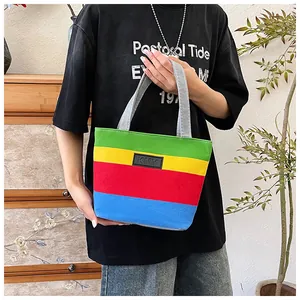Vibrant multi-color striped canvas tote bag held by a person in a casual lifestyle setting