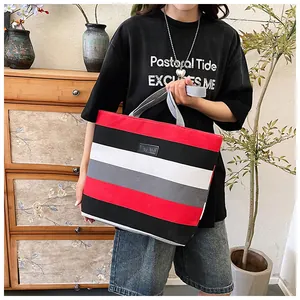 Detail view of large canvas tote bag featuring vibrant red and black stripes