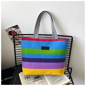 Detailed view of a vibrant rainbow striped canvas tote bag with KMY leather patch