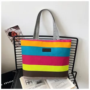 Detailed view of large vibrant striped canvas tote bag featuring KMY brand patch