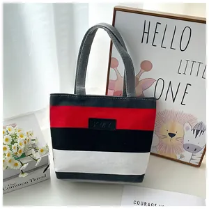 Red, black, and white striped canvas tote bag displayed in a cozy lifestyle setting