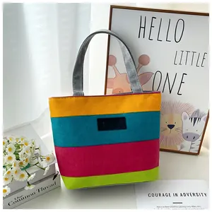 Detailed view of colorful striped canvas tote bag with gray handles on a table.