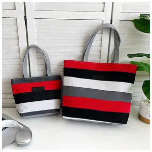 Detail of two striped canvas tote bags in red black and white with leather KMY tag