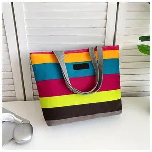 Vibrant multi-colored striped canvas tote bag displayed in a clean desktop setting