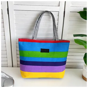 Front view of a vibrant large capacity rainbow striped canvas tote bag with grey handles