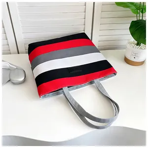 Detailed macro view of a red and grey striped canvas tote bag with sturdy handles.