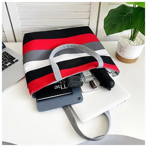 Detailed view of striped canvas tote bag showing large capacity for laptop and tablet.