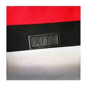 Detailaufnahme einer gestreiften Canvas-Tragetasche mit geprägtem Leder-Logo-Patch