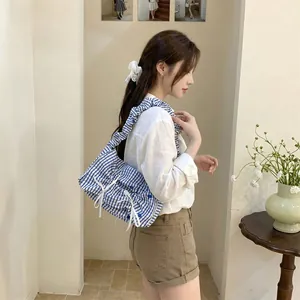 Asian female model wearing a blue and white striped ruffle shoulder bag with bows