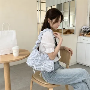Korean style striped ruffled shoulder bag with bow detail worn by a model in a cafe