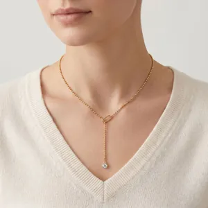 Close-up of a minimalist gold ball chain necklace with a drop pendant on a model