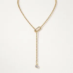 Elegant gold beaded Y-shaped necklace featuring geometric clasp and sparkling crystal.