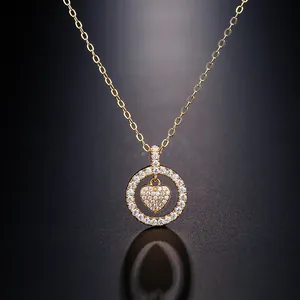 Close-up of golden circular pendant necklace with pave heart detail and reflection