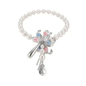 Elegant acrylic pearl necklace with floral pendant and instrument charms, holiday style.