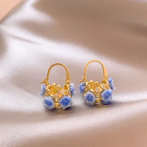 Detailed view of gold-tone flower basket earrings with blue roses and zircons on satin.