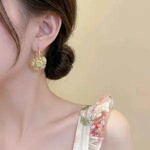 Elegant floral basket hoop earrings with zircons and pale green roses worn by model