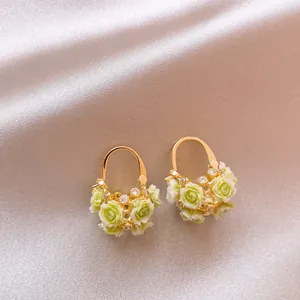 Detailed macro shot of romantic gold-tone zircon basket earrings with green roses
