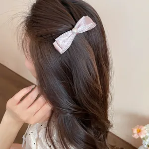 Detail shot of a pink cloth bow hair clip with elegant pearl embellishments on hair