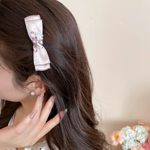Detailed view of an elegant pink satin bow hair clip with crystal flowers on hair