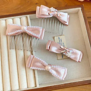 Close-up of pink satin bow hair combs and clips decorated with pearls and rhinestones