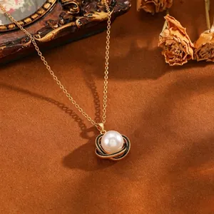 Detailopname van een elegante parelhanger met een zwart-gouden gedraaide bloemzetting