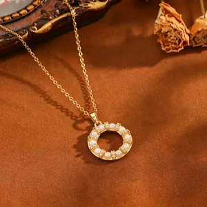 Detailweergave van een goudkleurige ronde hanger ketting met parels en kristallen.