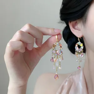 Detailed view of elegant gold tassel earrings with pink crystals and teardrop beads
