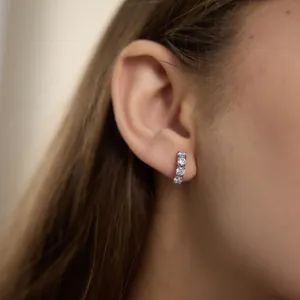 Gros plan d'une boucle d'oreille en acier inoxydable avec des zircons clairs.