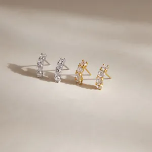 Détail de boucles d'oreilles courbées en acier inoxydable avec cinq zircons ronds
