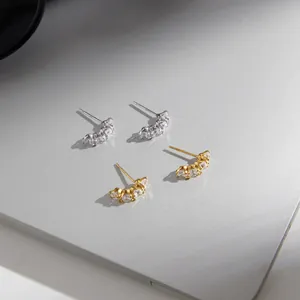 Gros plan de boucles d'oreilles courbées en acier inoxydable avec zircons or et argent.