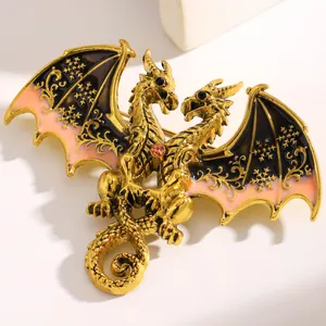 Detailed view of a gold double-headed dragon brooch with enamel wings and pink gem.