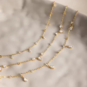 Primer plano de tobilleras de acero inoxidable chapado en oro 18k con circonitas