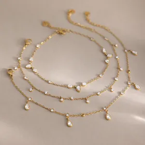 Detalle de tobilleras en acero inoxidable chapado en oro de 18k con gotas de circonitas