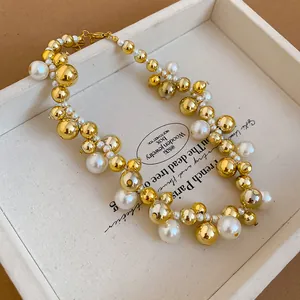 Primo piano dettagliato di una collana di perle e grani dorati in un portagioie bianco