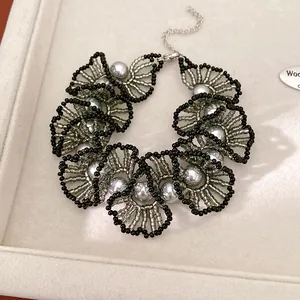 Vue détaillée du collier en dentelle perlée avec perles argentées et perles noires.