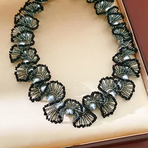 Gros plan d'un élégant collier en dentelle de perles de verre fait main avec perles grises