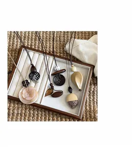 Artistic collection of irregular Maillard style long necklaces on a wooden display tray