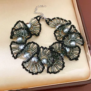 Vue détaillée d'un collier en dentelle perlée avec des perles grises et des perles noires.