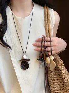 Close-up detail of irregular long necklaces with earth-tone pendants worn by a model.
