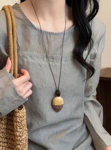 Detail view of Maillard style long necklace with acorn shaped wooden pendant on model