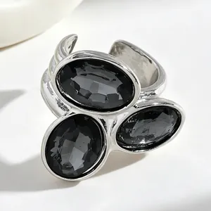 Close-up view of an irregular silver-tone ring set with three oval faceted black stones.