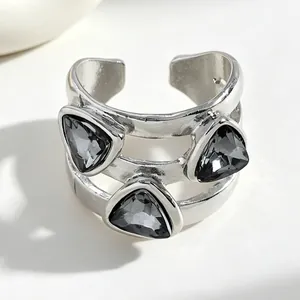 Close-up of a silver open ring featuring three triangular black faceted stones.