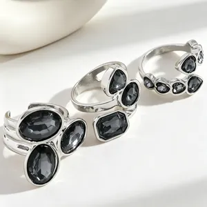 Close-up of irregular silver-toned rings set with faceted black acrylic gemstones.