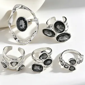 Detailed view of five silver-toned rings set with dark grey geometric crystals