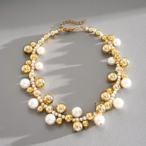 Vista dettagliata di una collana retrò con perle bianche e sfere di metallo dorato