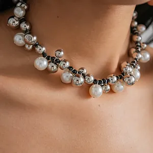 Dettaglio ravvicinato di una collana retrò con perline d'argento e perle bianche al collo