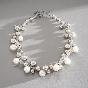 Dettaglio macro di una collana con perle e sfere d'argento su pelle grigia martellata